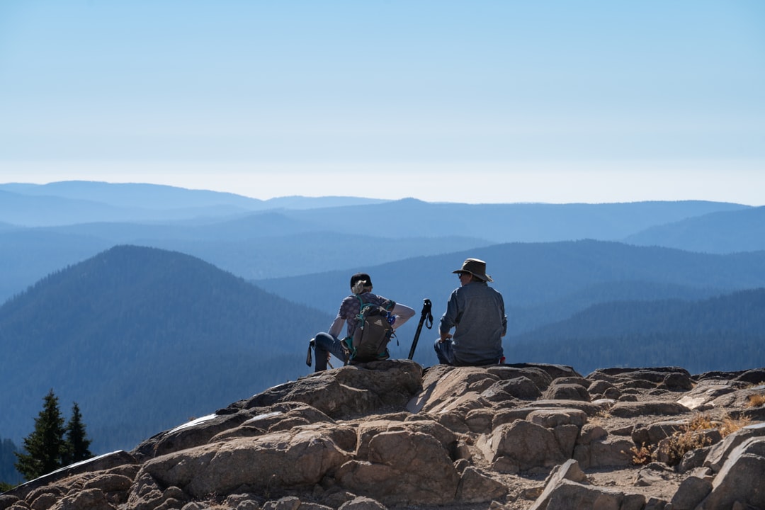 Two people on a hike, sitting down, overlooking a vista.